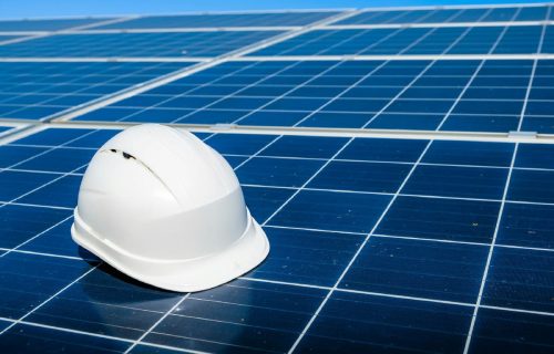 Casque de sécurité blanc posé sur un panneau solaire, symbole de protection sur les chantiers.